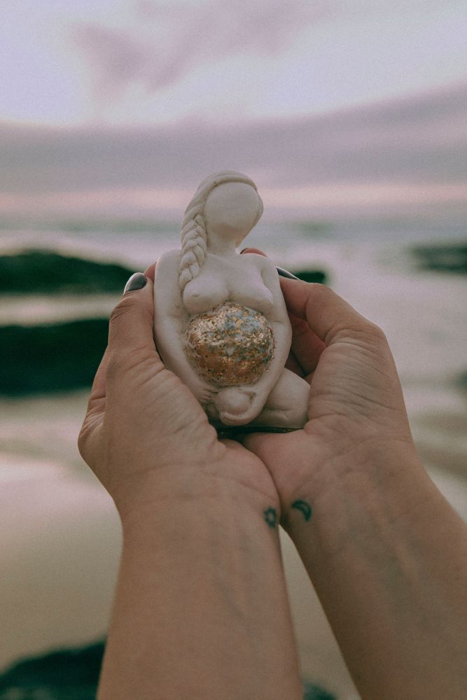 Mãos a segurar uma pequena figura feminina