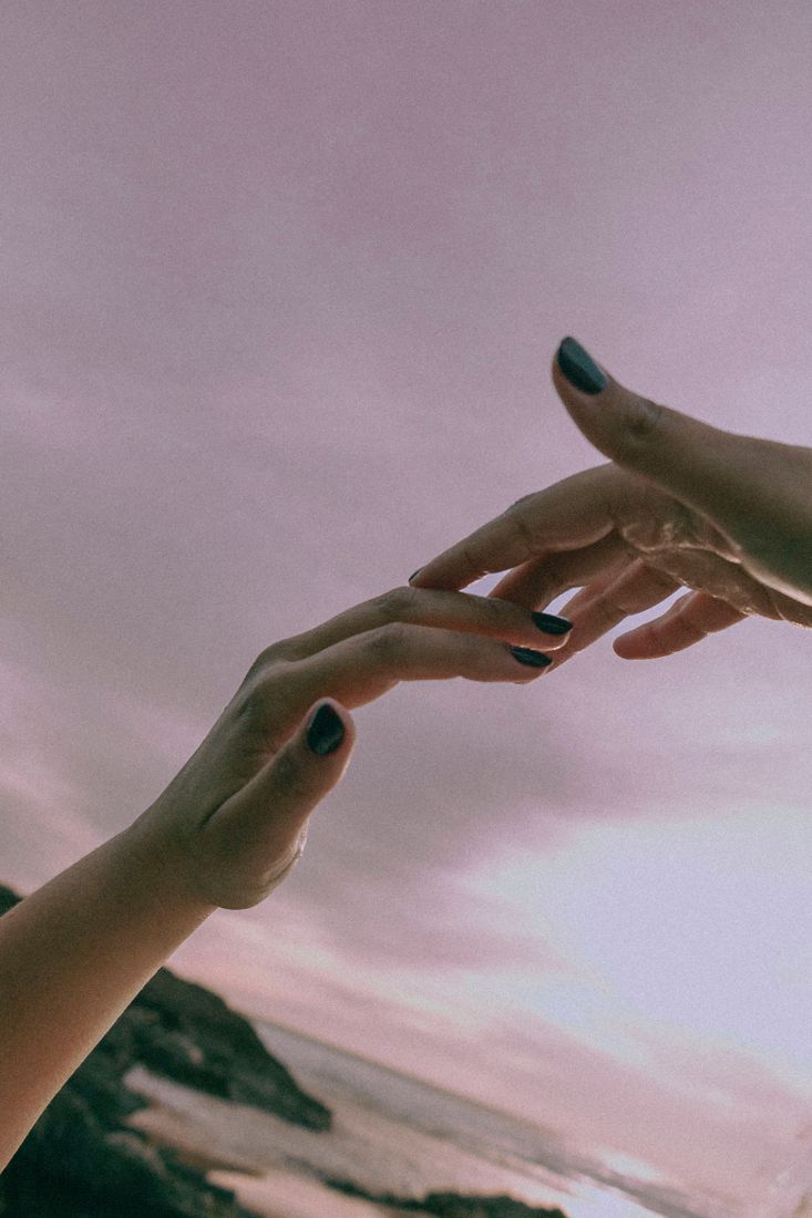 Mãos contra um céu rosa