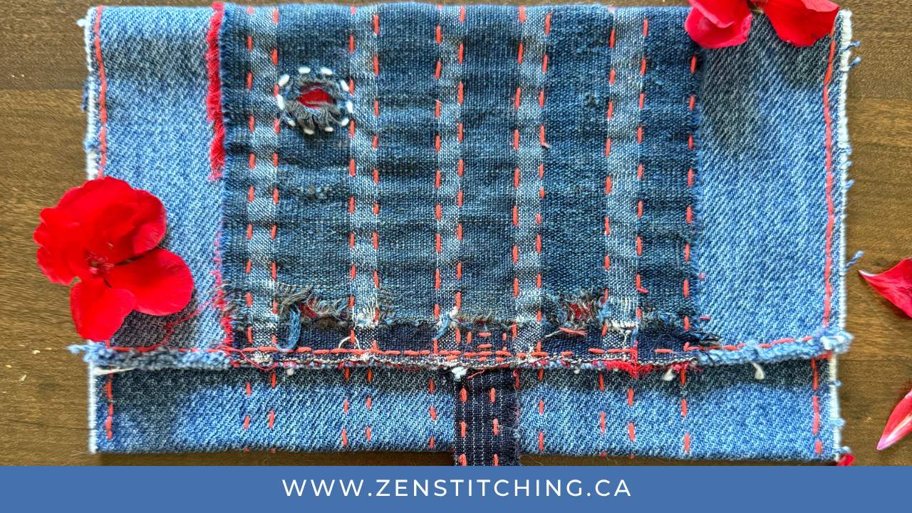 A boro-inspired, foldover-style pouch lays on a wooden tabletop. The bottom reads "www.zenstitching.ca"