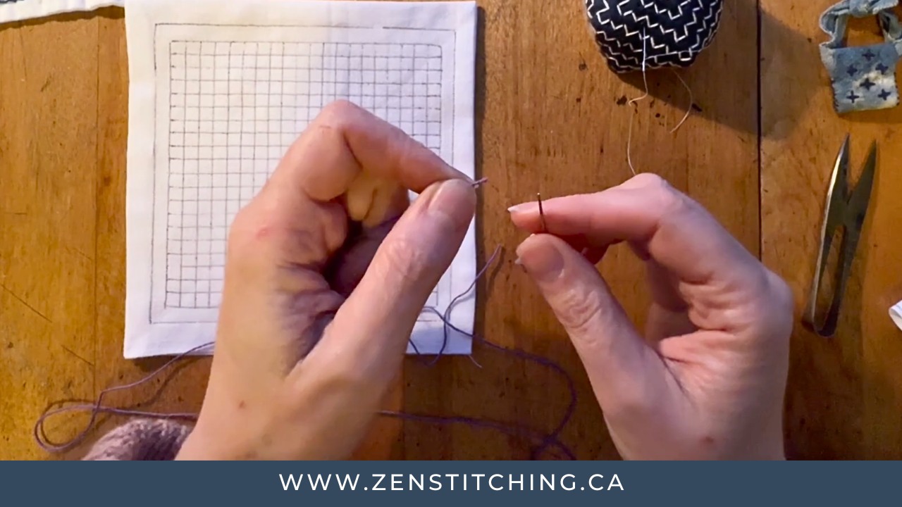 Kate Ward's hands hold sashiko thread and a needle, poised for threading.
