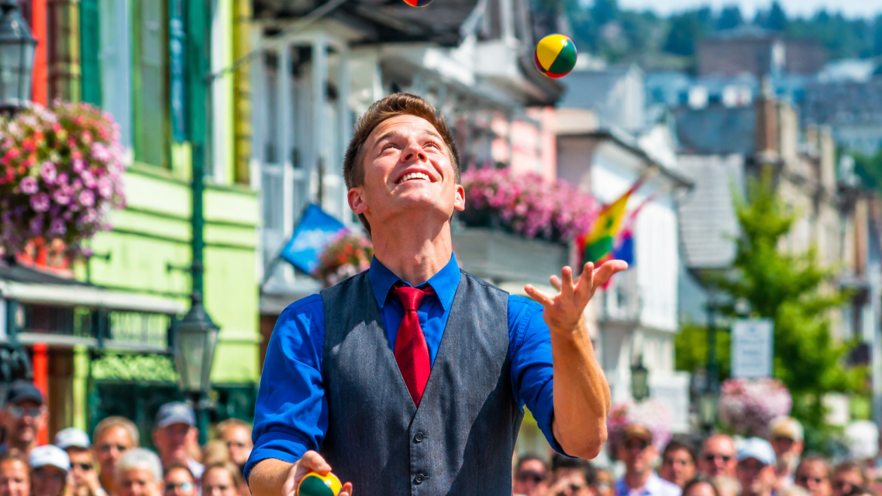 A street performer joyfully juggling colorful balls before a crowd, illustrating how mastery is built through practice, focus, and patience