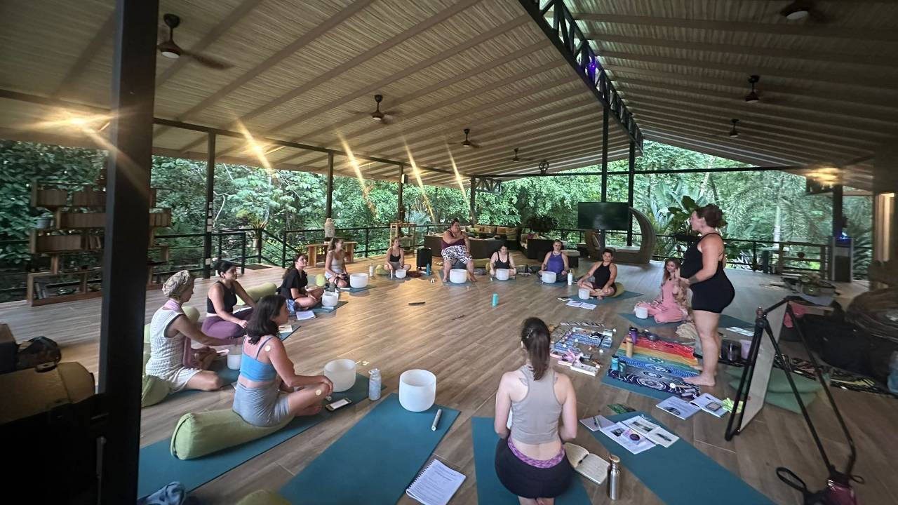 Woman holding a singing bowl in a yoga studio, sound healing practitioner training