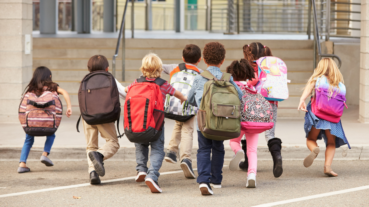 A gorup of children running towards the school doors.