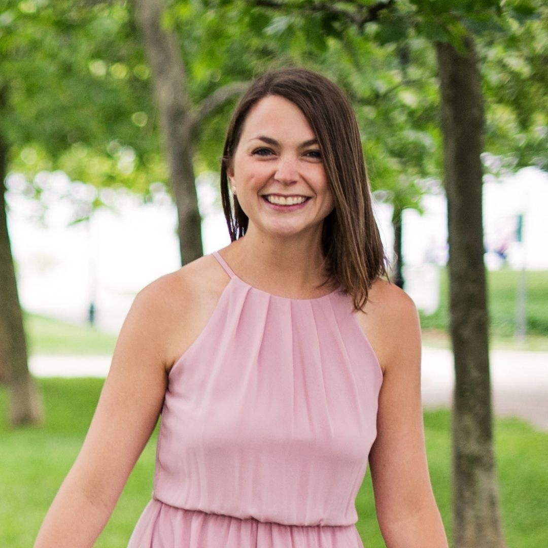 Photo of Michaela DiGionvittorio, Illustrator. DiGionvittorio smiles outside while wearing a light pink dress.