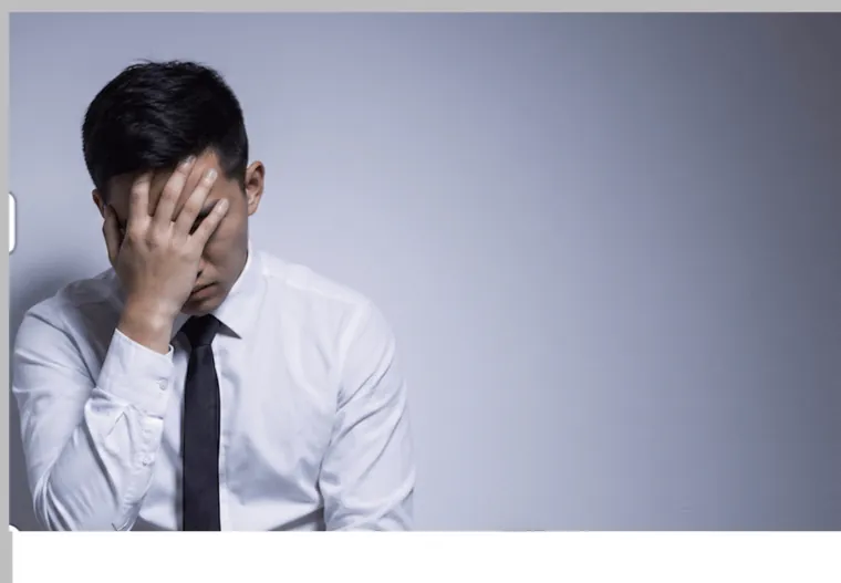 男性專業人士在辦公室以手扶額，因形象無法說服顧客而困擾