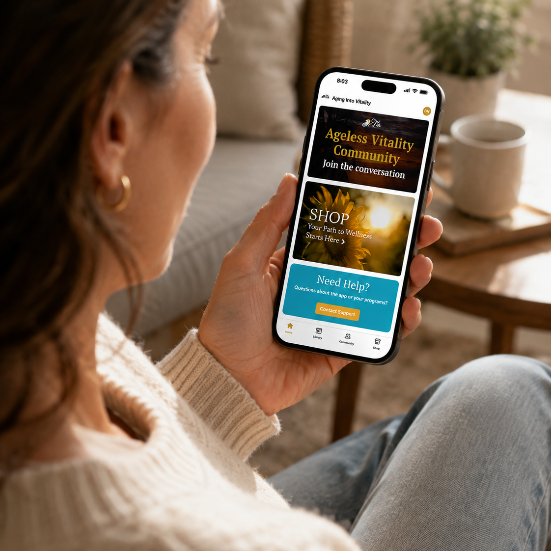 Woman using the Ageless Vitality Community app on her phone, highlighting easy access to wellness resources, support, and community through Aging Into Vitality®.