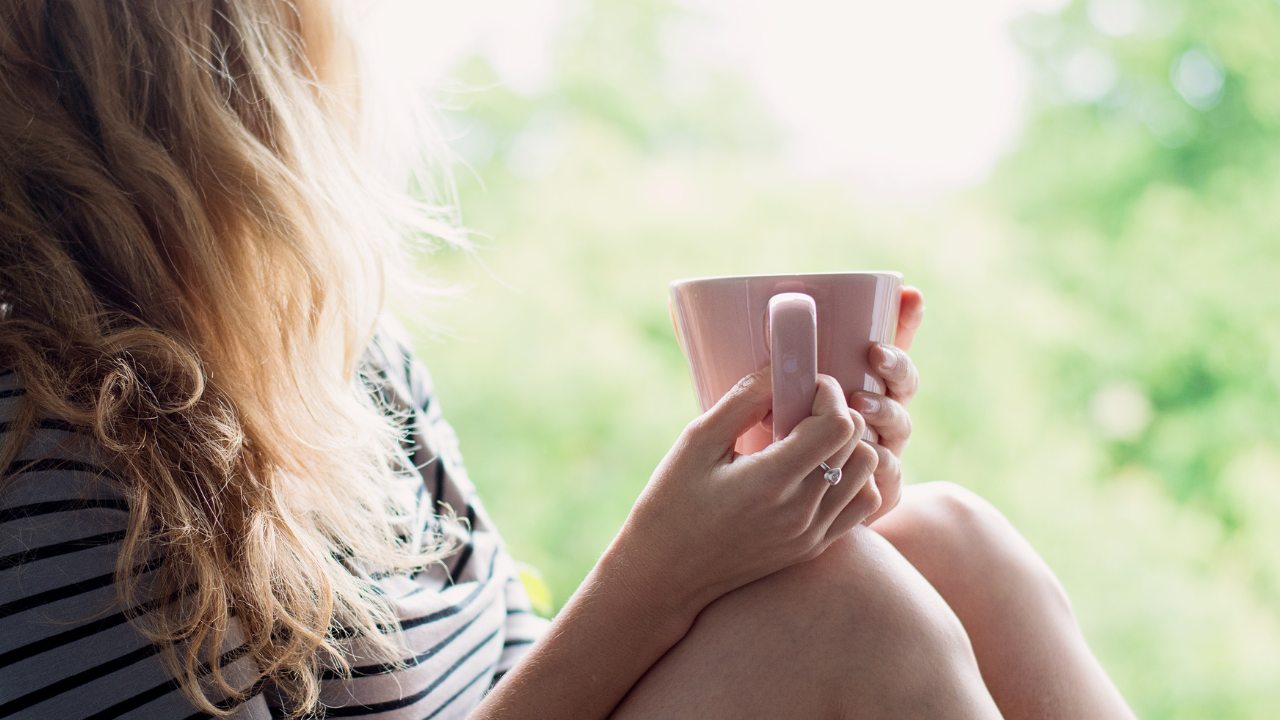 Ocea Marie article on gratitude, awareness and everyday wellbeing. Woman sitting looking away out of a window holding a pink mug.
