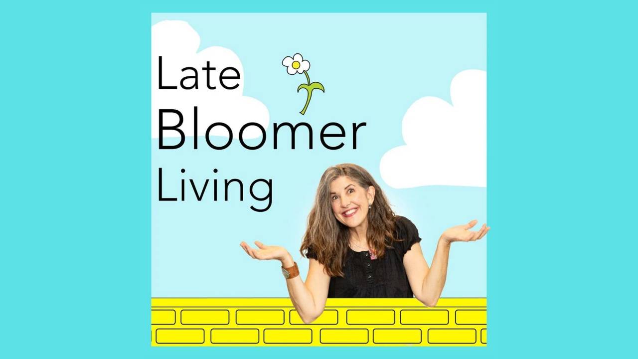 Late Bloomer Living cover art: host Yvonne Marchese smiles and shrugs behind a yellow brick wall under a blue sky with clouds and a daisy.