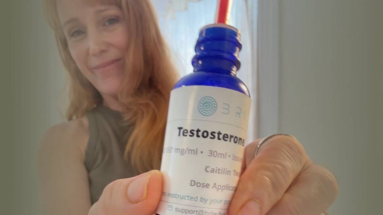 Woman holding a prescription testosterone hormone replacement therapy (HRT) bottle during a discussion about hormone health, menopause, and personalized wellness care