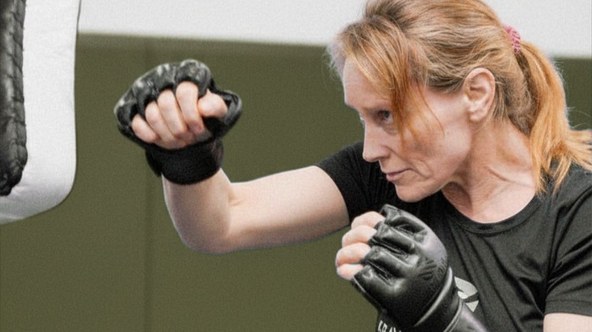 Woman practicing Krav Maga with a high kick to build strength, bone density, balance, and longevity through impact training.