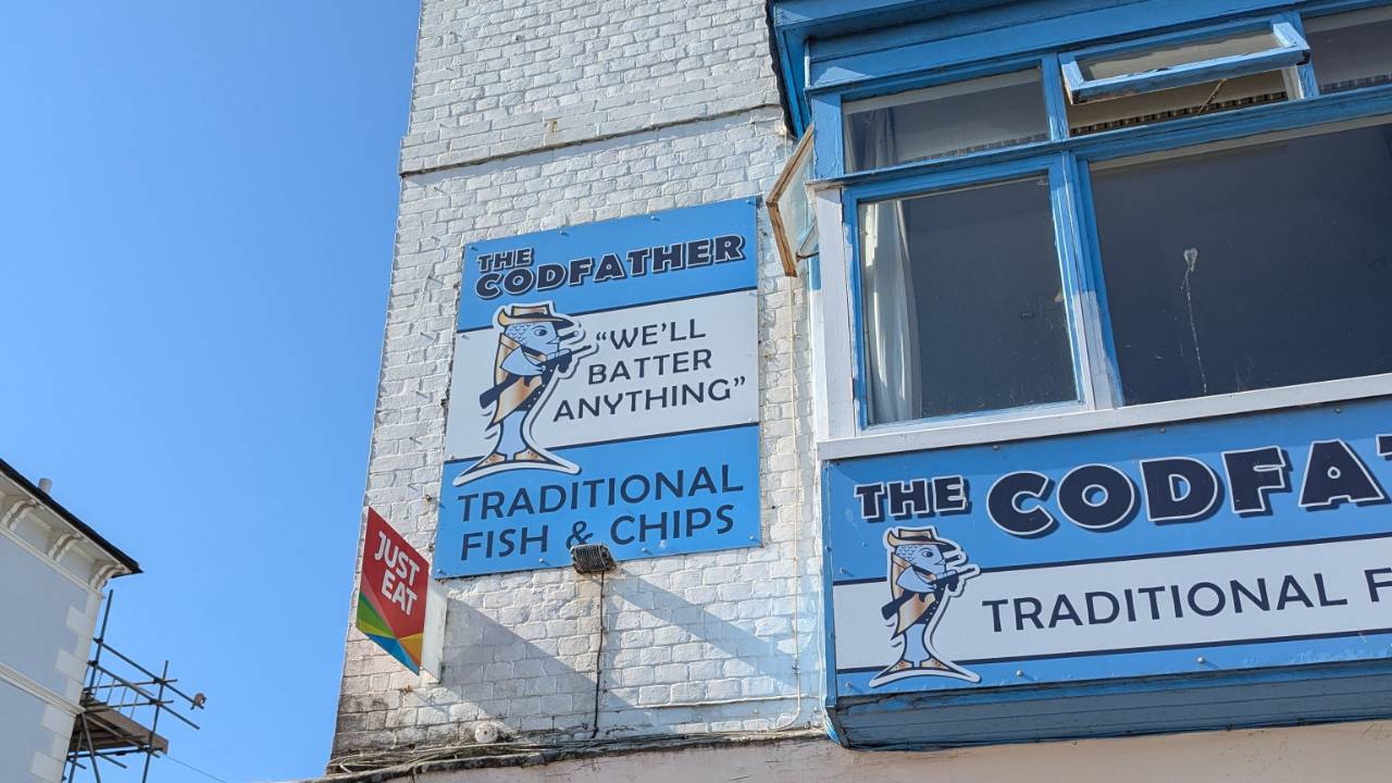 Blue and white fish and chip shop with a clever 'The Codfather' sign, representing the power of memorable words, microscripts and the stories we tell ourselves.