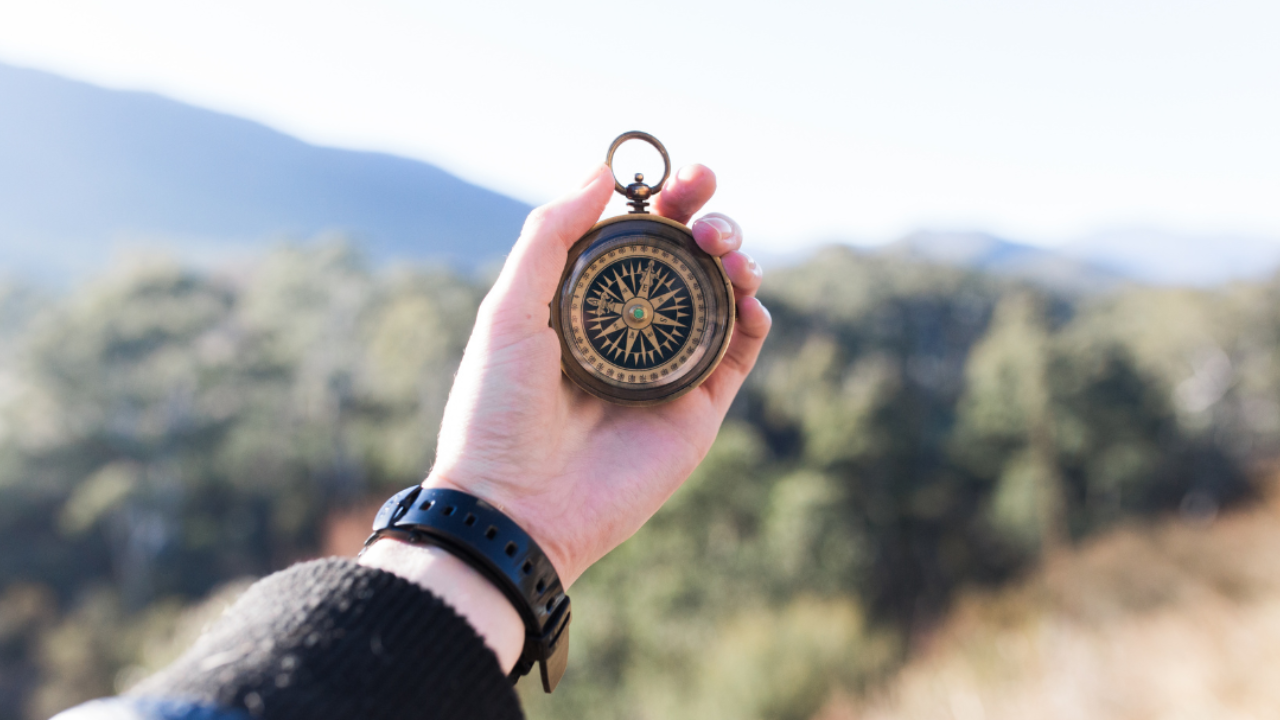 Person holding a compass outdoors in nature, symbolising direction and financial decision making and long term investing strategy
