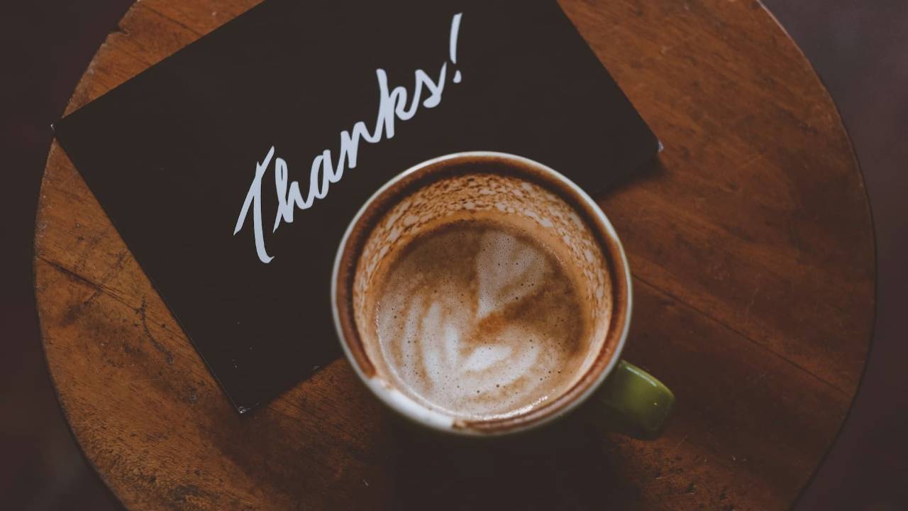 a single thank you card and a coffee mug in front of it, late afternoon light