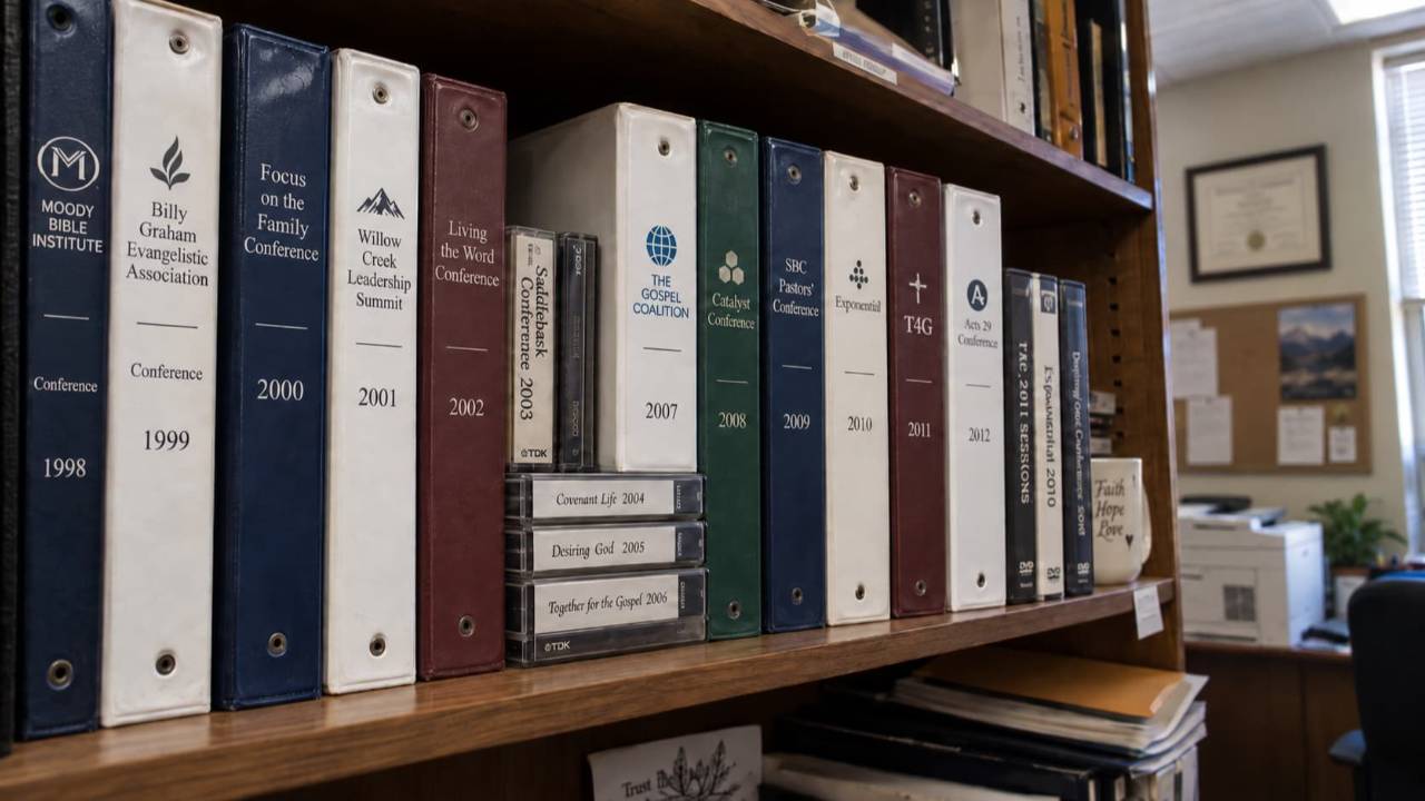  Shelf of church conference binders, cassette tapes, and DVDs collected from ministry conferences between 1998 and 2012