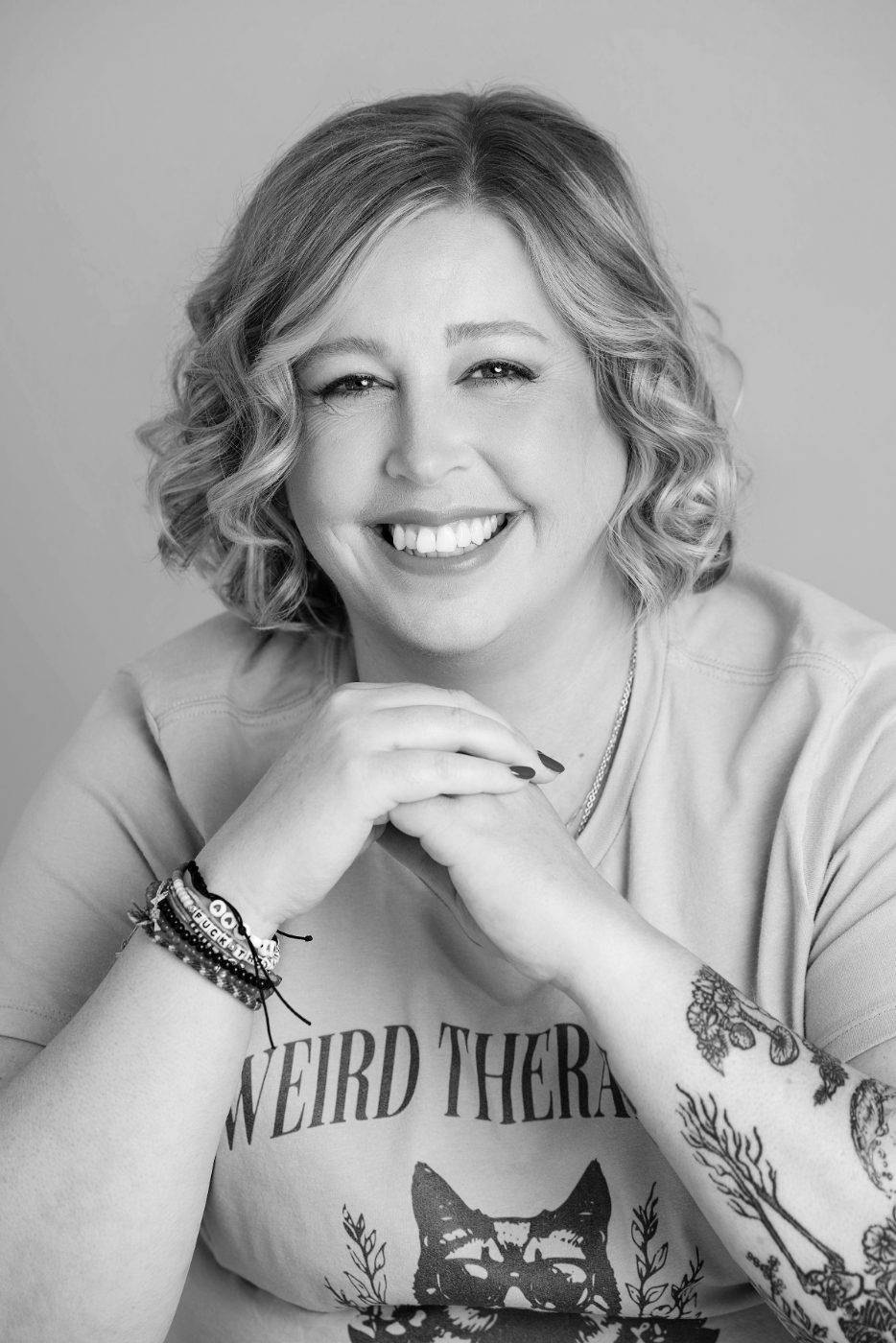 Black and white portrait of Becca Gerlach, clinical supervisor and EMDR consultant, smiling with her chin resting on her hands