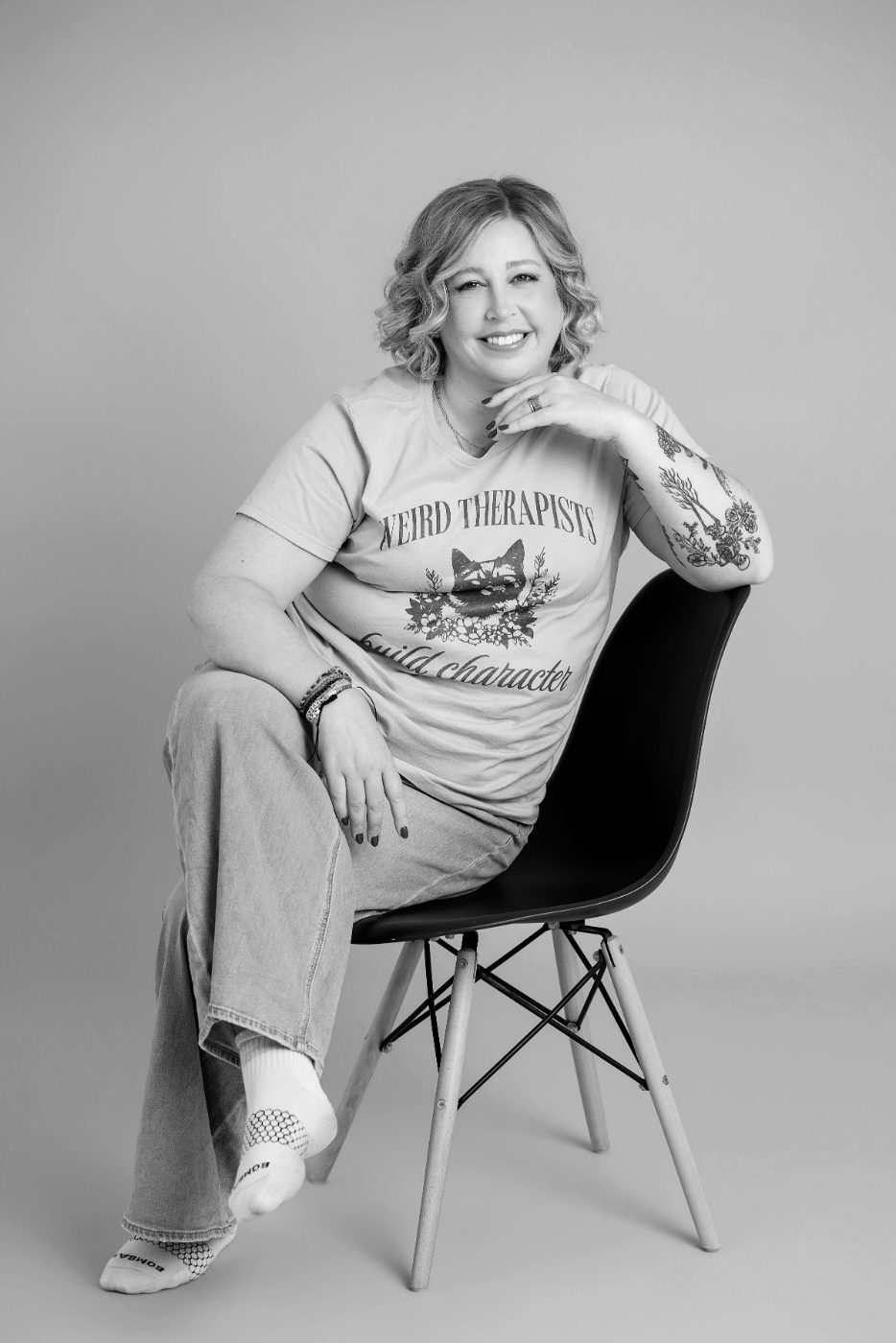 Becca Gerlach, LMSW, burnout recovery therapist, sitting on a black chair in a black and white portrait