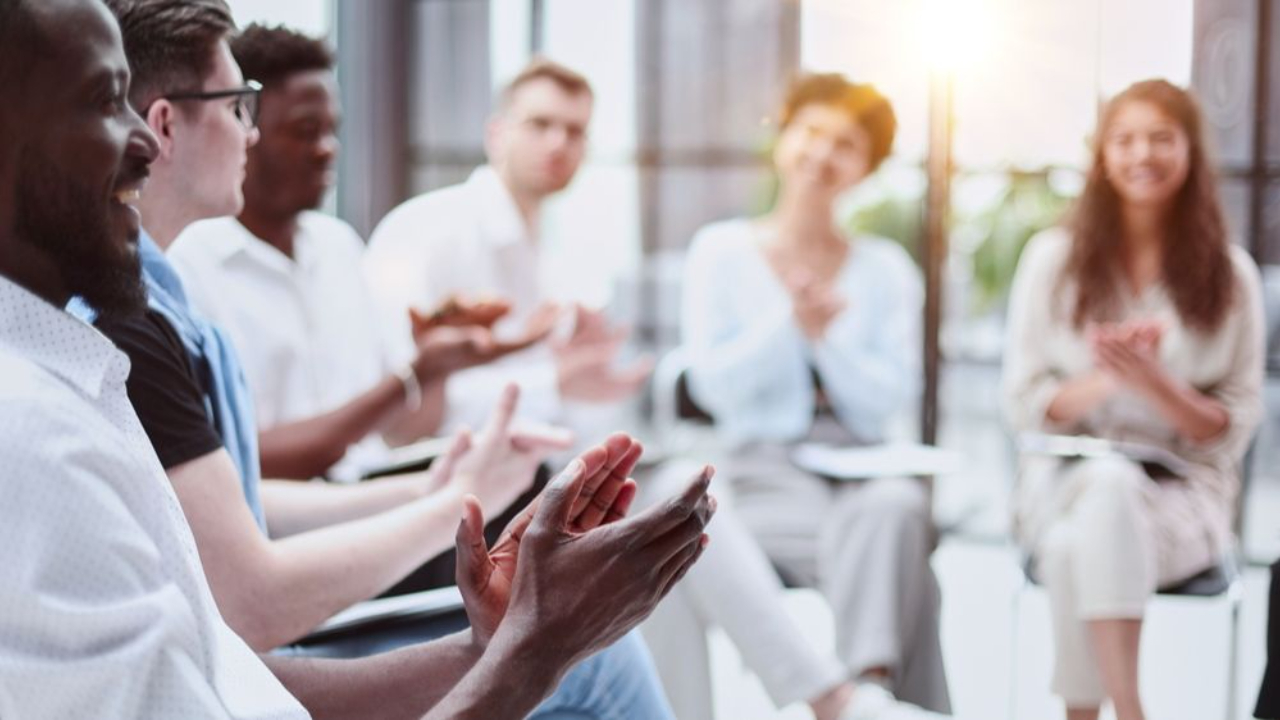 Team members clapping at a work meeting.
