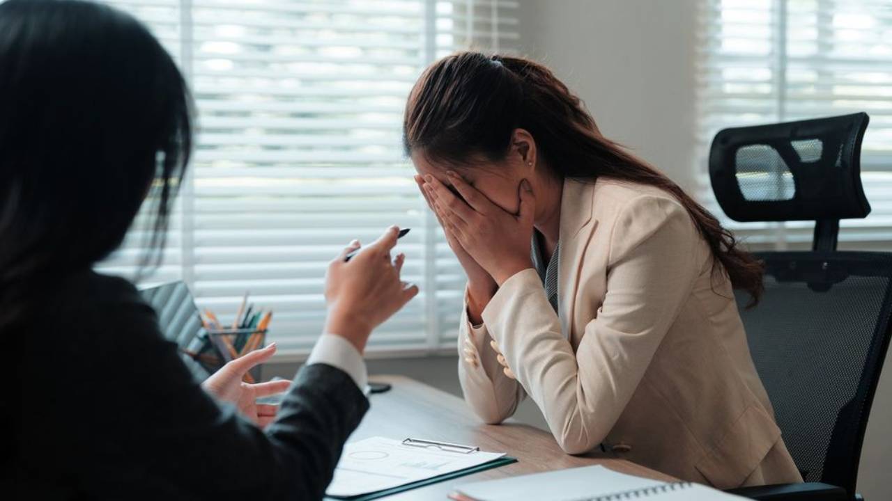  Image of employee covering her face during a difficult conversation with her manager.