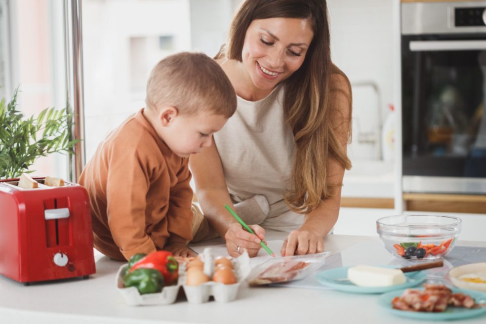 A young boy in the kitchen with his mother