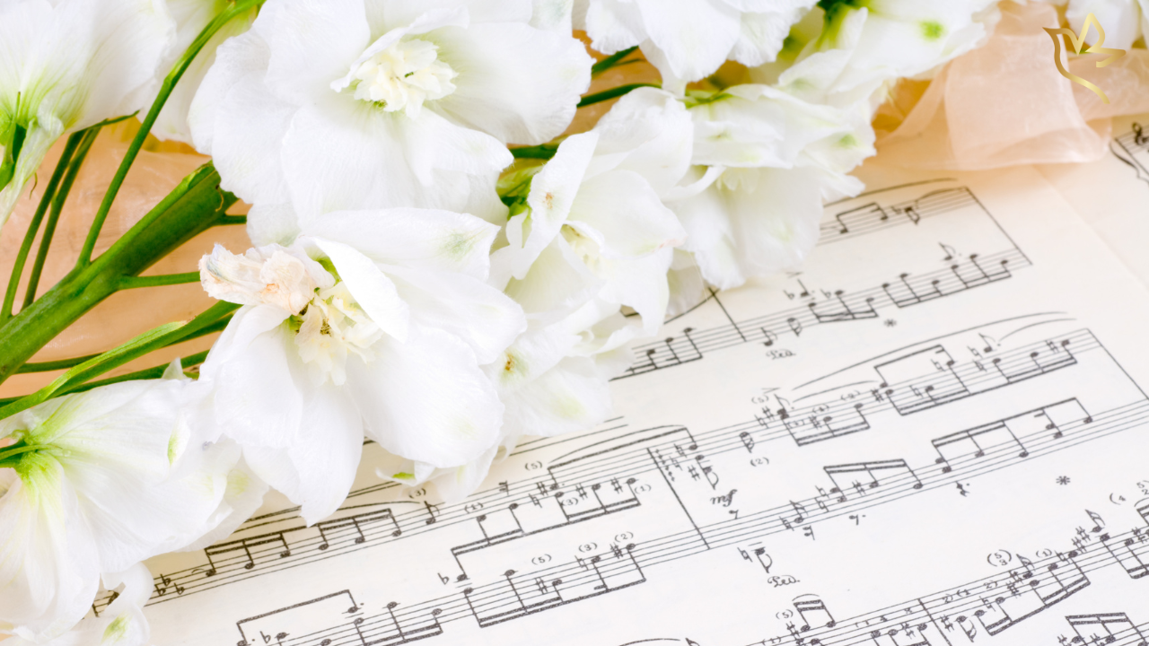 White flowers resting over sheet music representing meaningful funeral songs and music to honor a mother