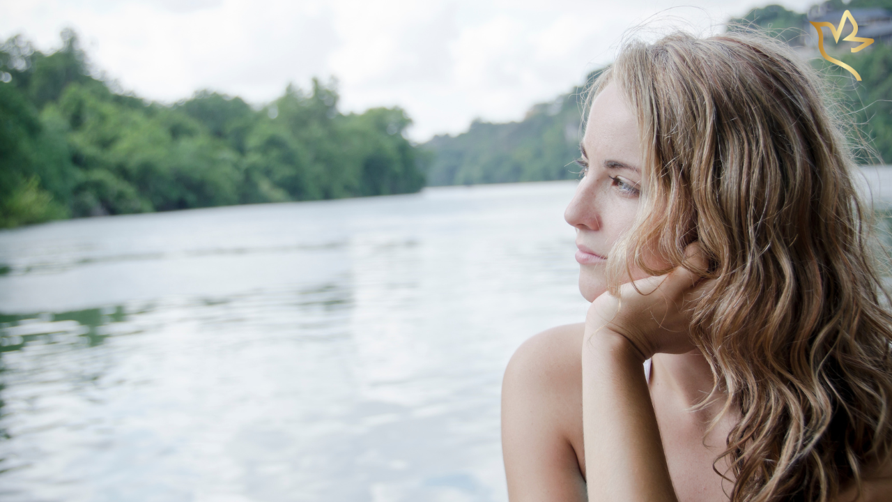 A woman gazes thoughtfully across a quiet river, reflecting on unexpected memories, enduring love, and the gentle journey of healing after loss.