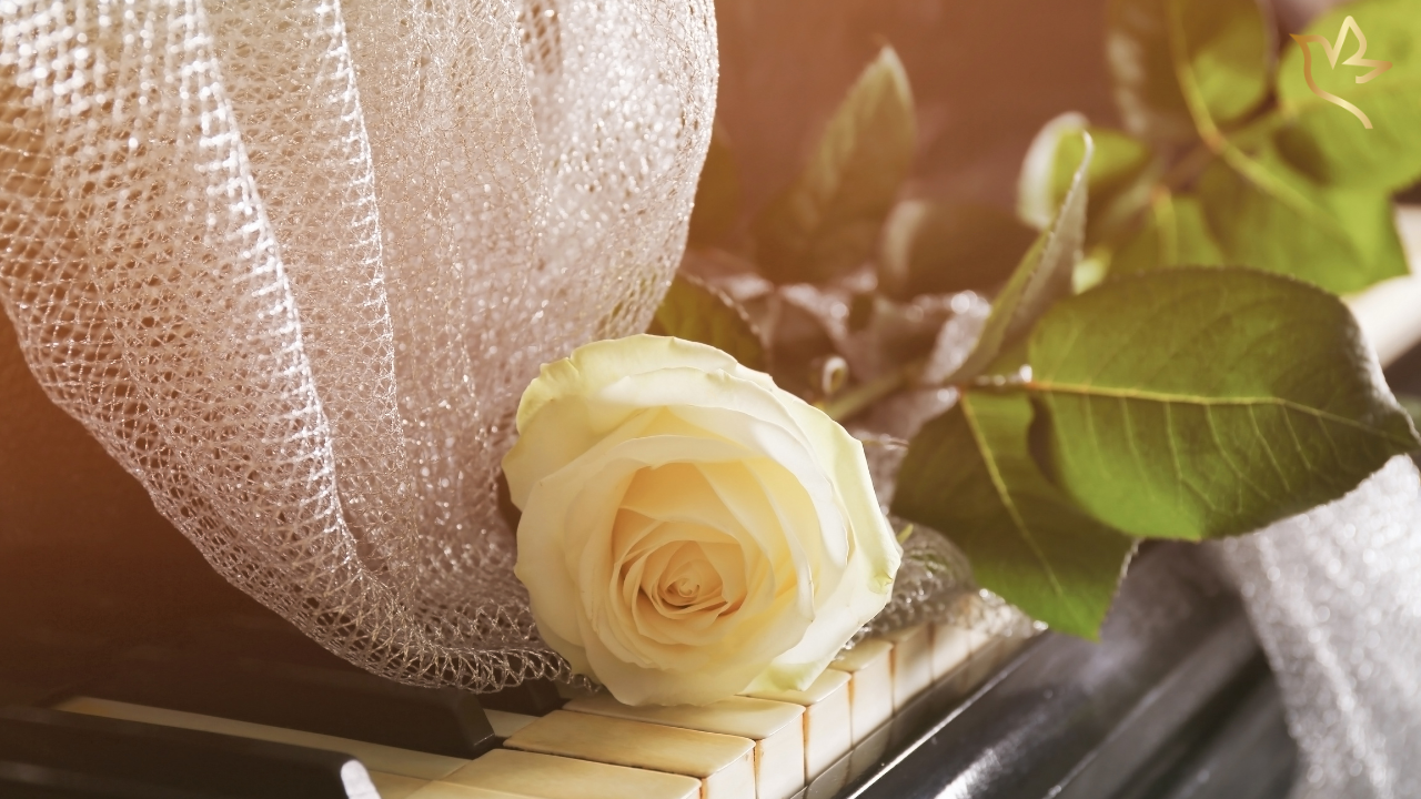Cream rose resting on piano keys representing meaningful funeral songs and music to honor a grandmother.