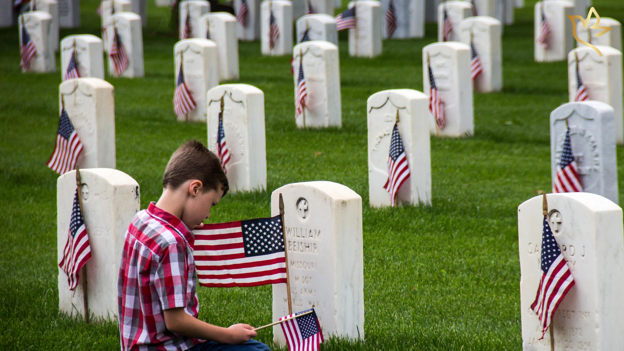 Young boy placing an American flag at a Veteran's grave in a national cemetery, honoring military service while representing Veterans burial and memorial benefits.