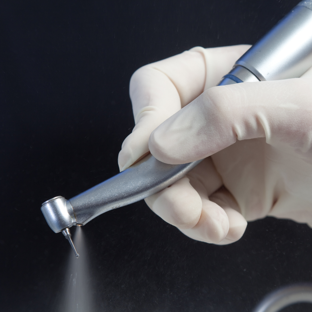 ▶  gloved hand holding dental drill