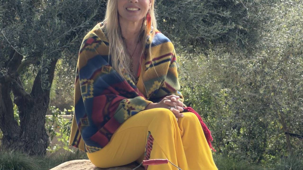 Dawn Light Amora sitting outdoors among olive trees, reflecting on the mother wound and returning home to herself.