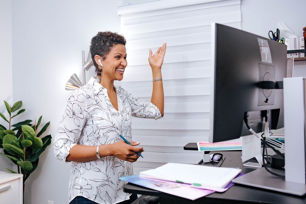 A woman standing in front of her computer gesturing as she delivers a workshop