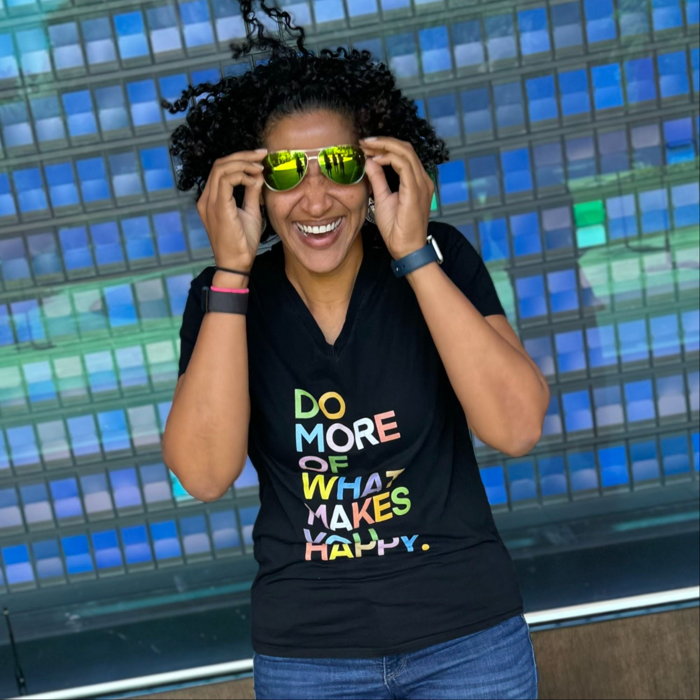 Woman smiling with hands on sunglasses 
