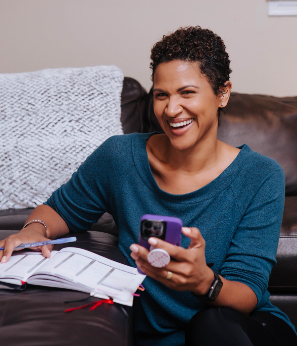 Woman sitting on the floor, holding her phone, smiling 