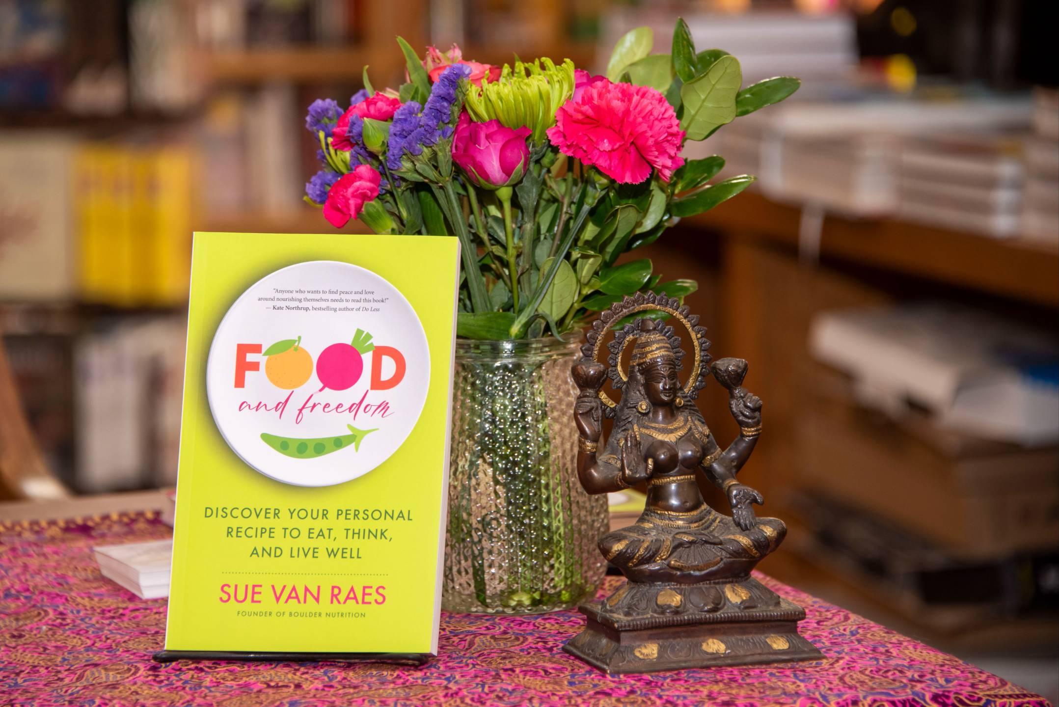 Food and Freedom by Sue Van Raes, beside flowers and a goddess statue