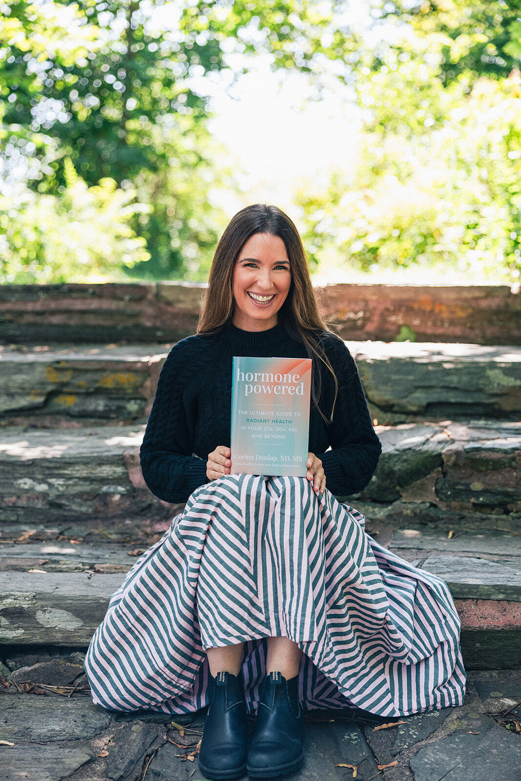 Dr. Corina Dunlap holding her book, Hormone Powered