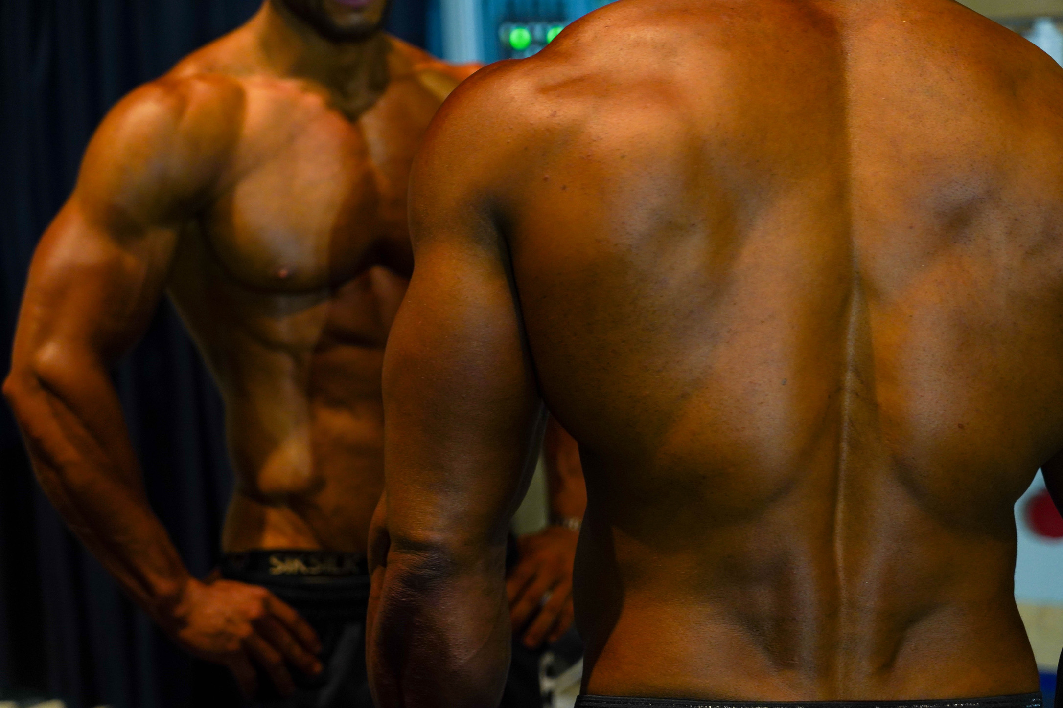 Male physique competitors preparing backstage