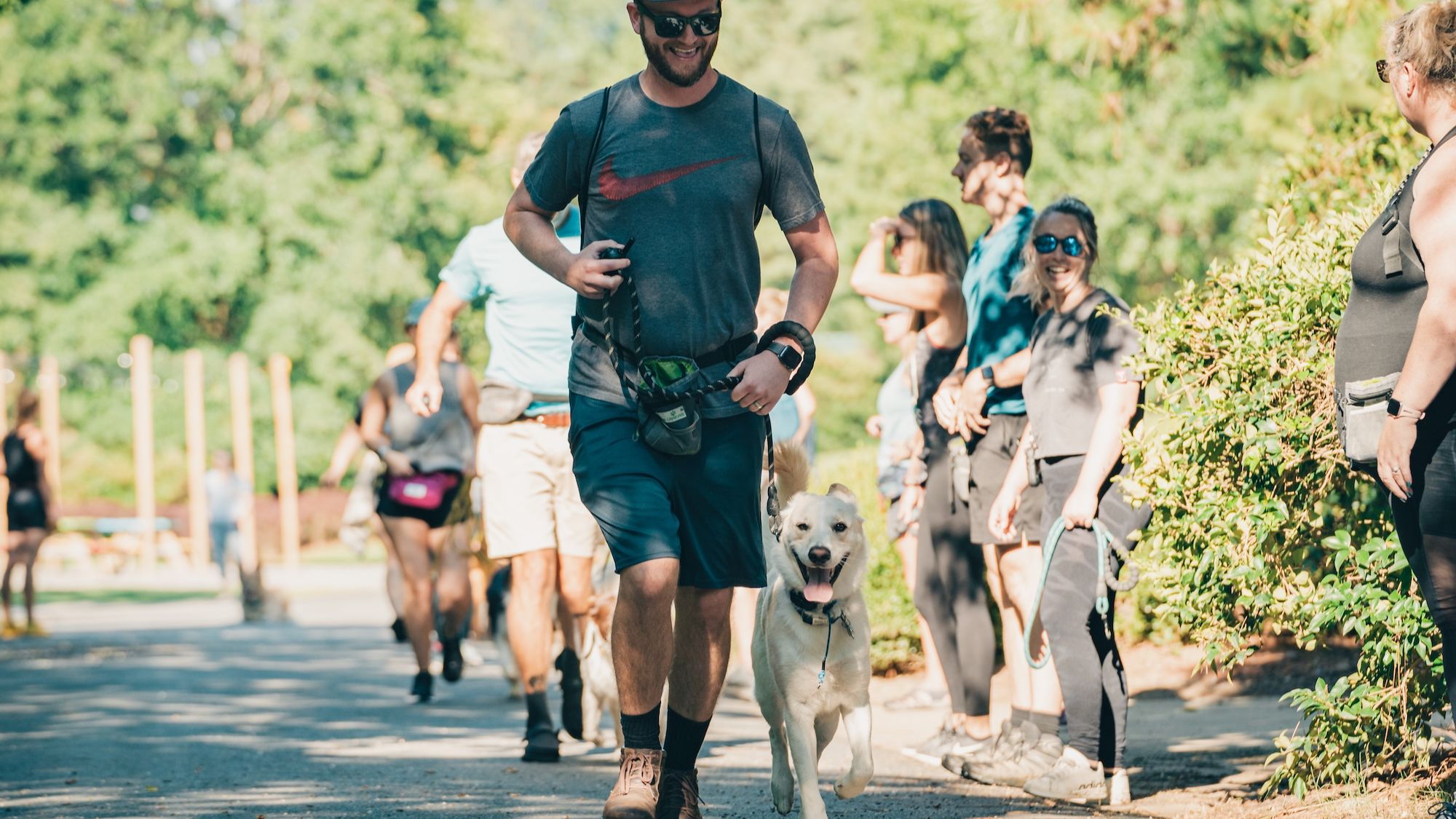 White mixed breed KeenDog in training running next to male owner at group class