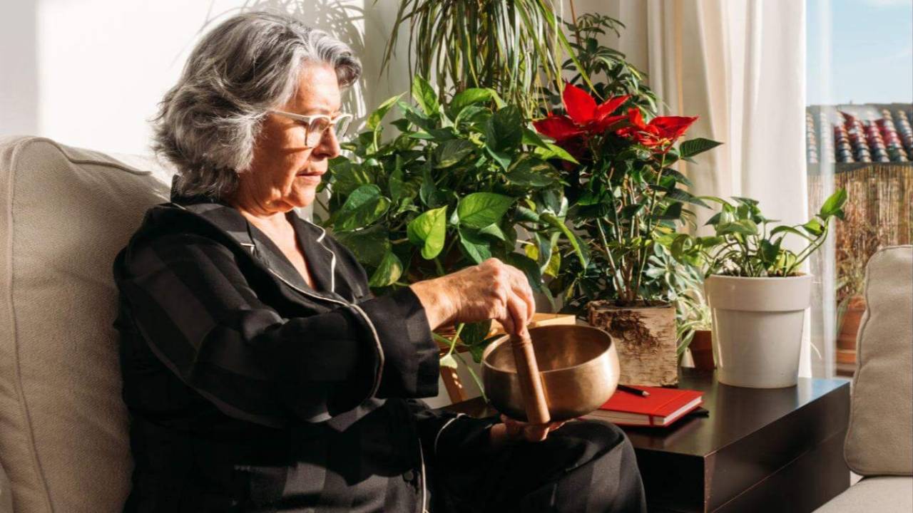 Mature adult practising sound healing at home with a crystal singing bowl