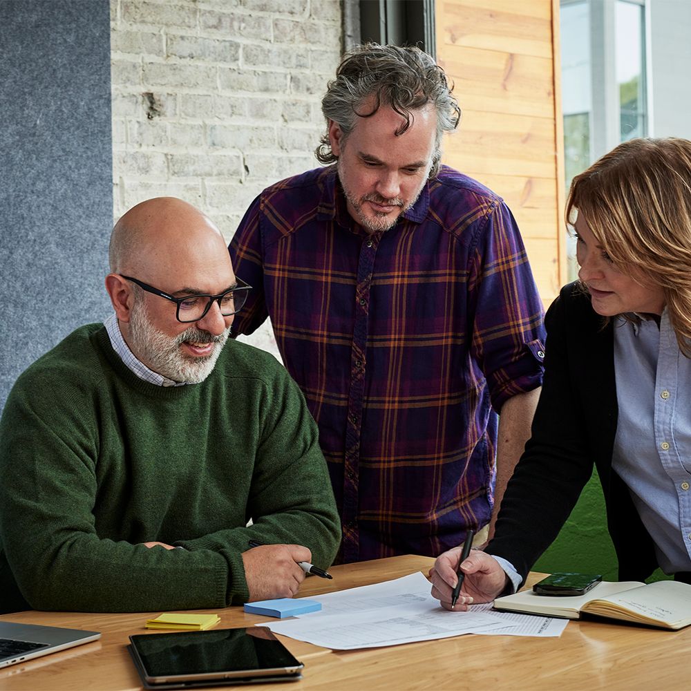 Paul Miklautsch of BOLDR Product Management smiling and engaging in conversation with two clients.