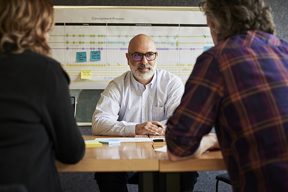 Paul Miklautsch of BOLDR seated at a desk across from two clients