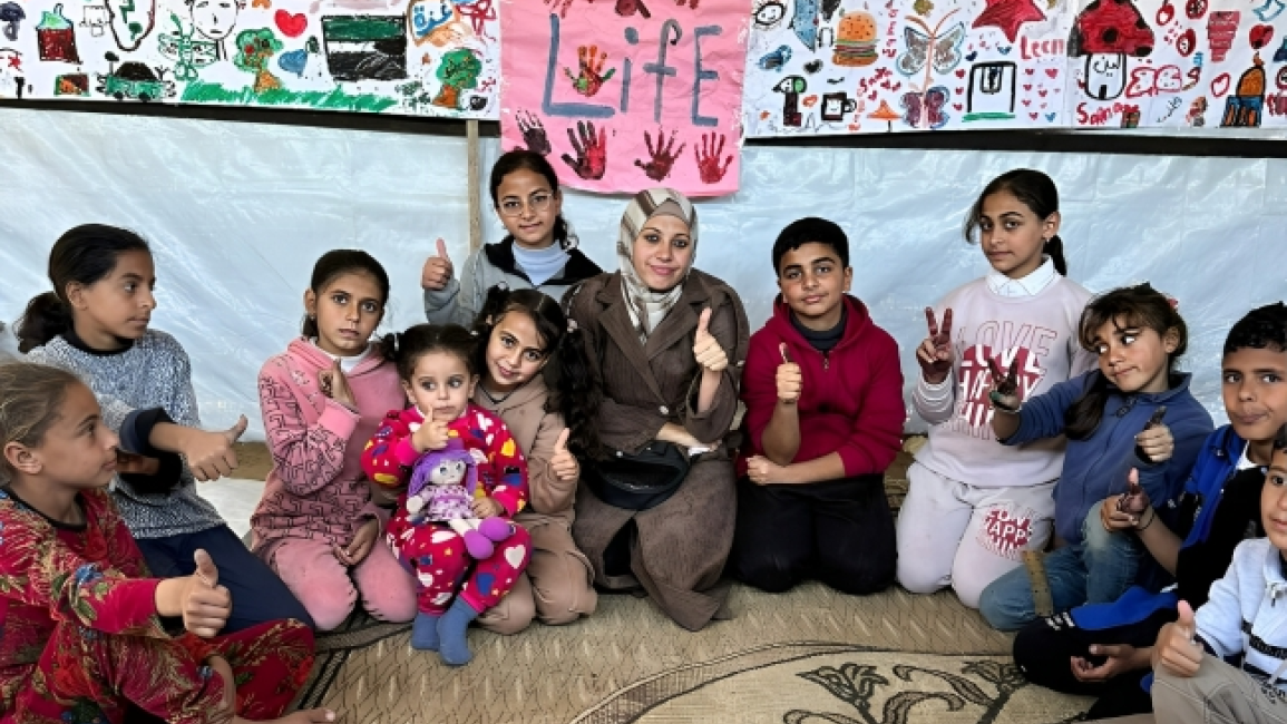 Community leader with children in a camp session in Gaza