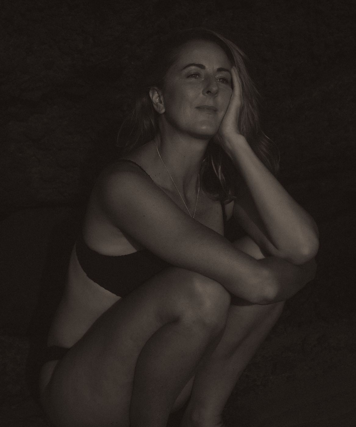Rachel, crouching, chin resting on her hand