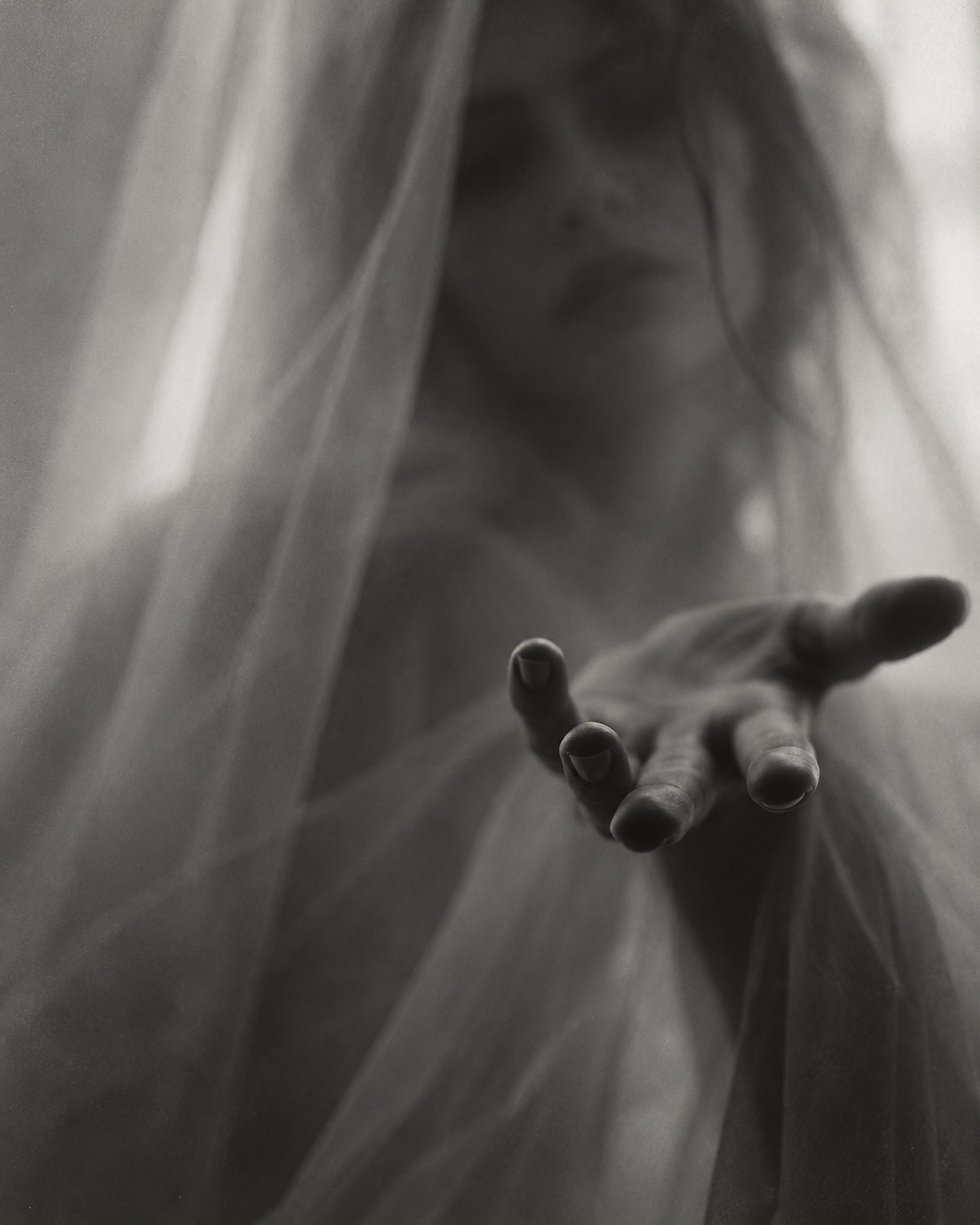 A hand pushing through a veil
