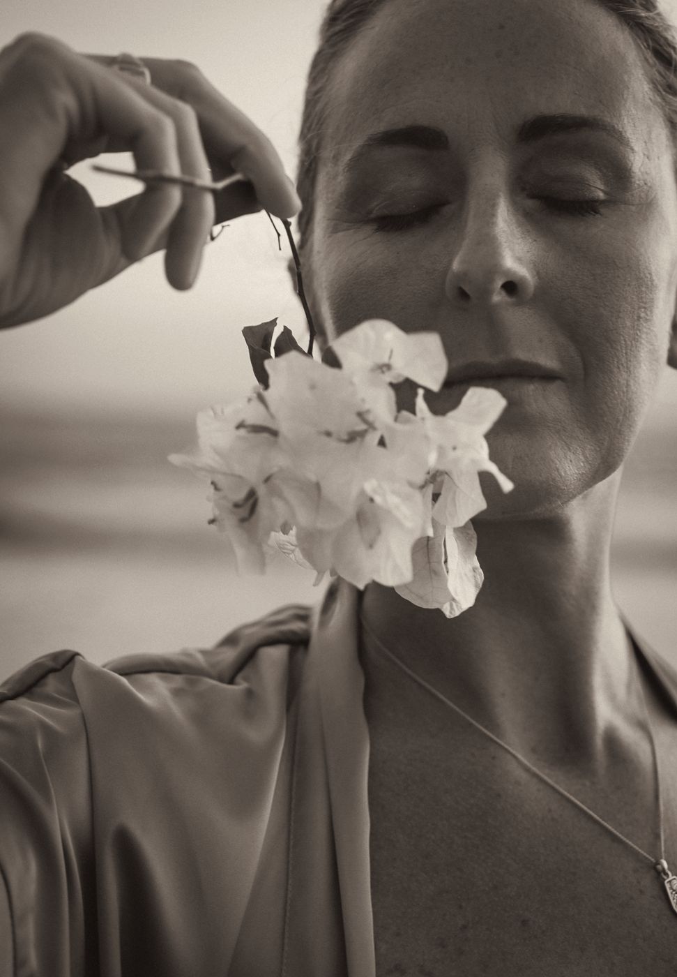 Rachel, eyes closed, holding a white flower to her lips