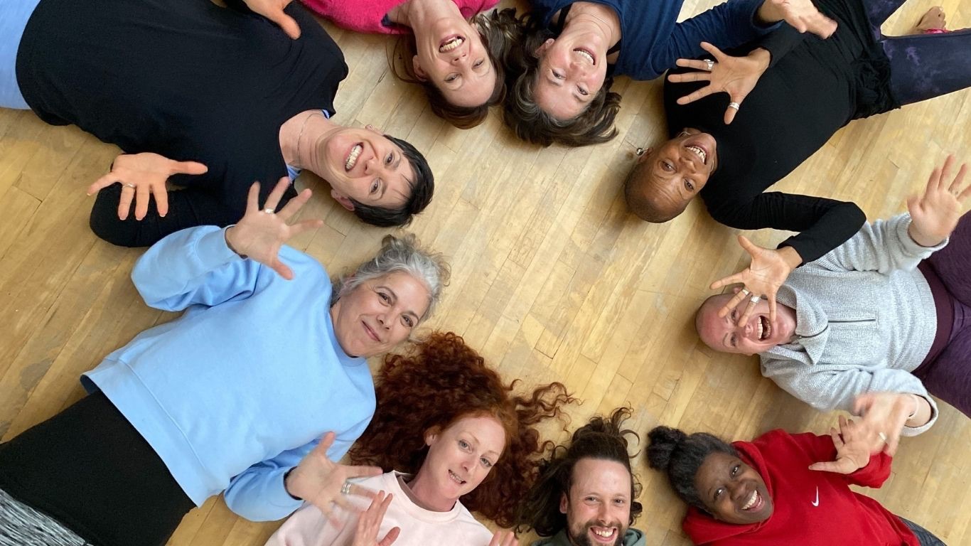 Group of yoga teacher trainees smiling in a circle