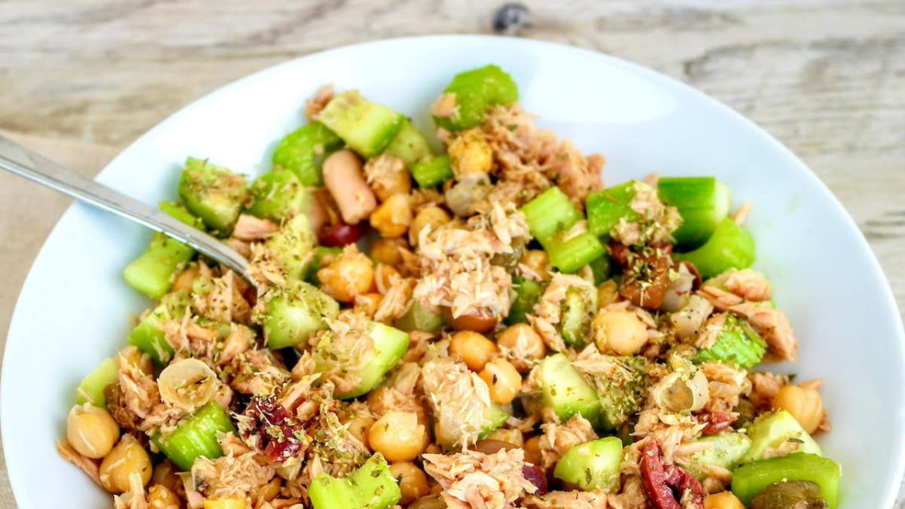 Cold salad bowl containing flaked canned tuna, rinsed chickpeas, diced English cucumbers, halved Kalamata olives, and olive oil dressing.