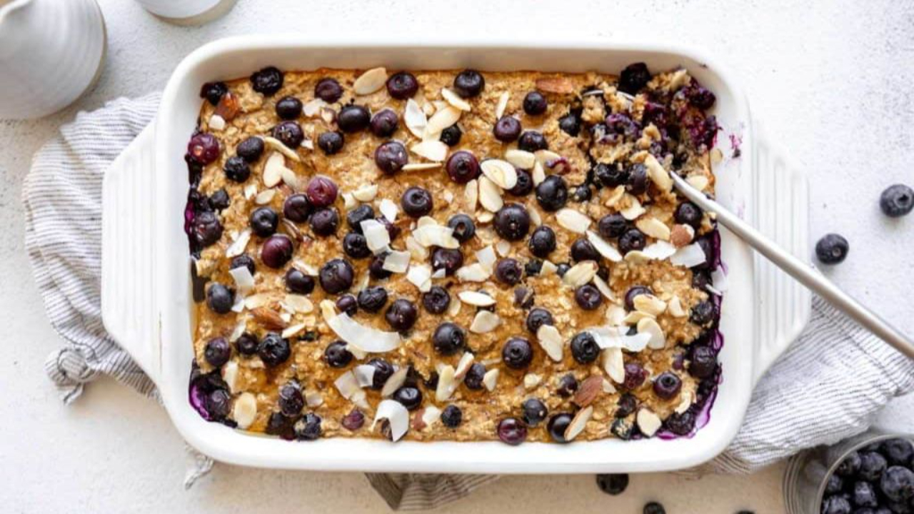 Single-serve protein baked oatmeal in an oven-safe ramekin topped with fresh bubbling blueberries and rolled oats.