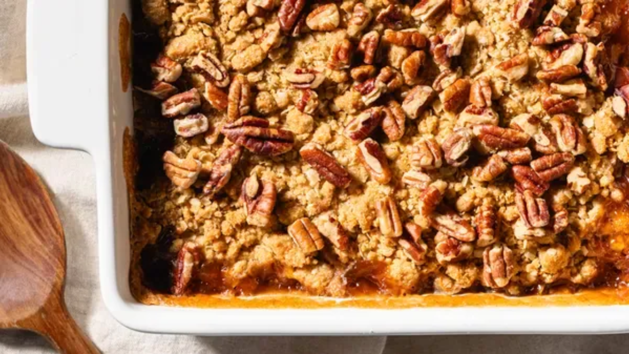 Warm baked sliced Honeycrisp apples in a small baking dish topped with a golden brown crispy rolled oat and pecan crumble.