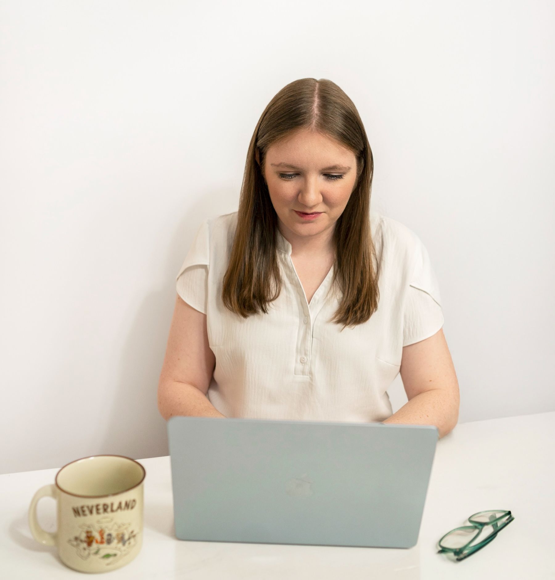 girl typing on laptop with mug and glasses
