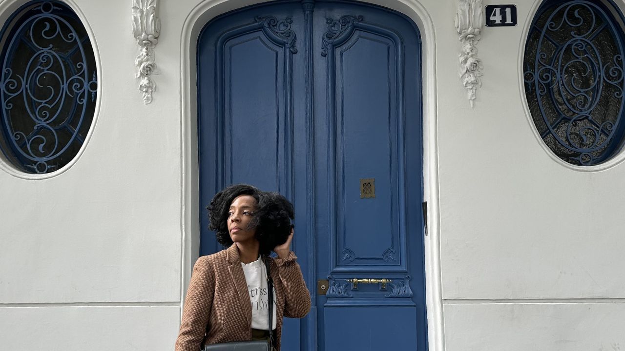 image of Kleidi Jeen walking in front of blue doors in Paris