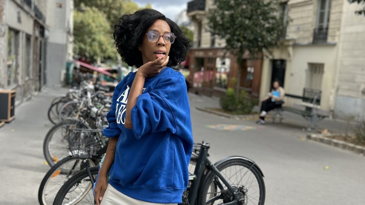 Kleidi Jeen standing in a blue sweatshirt after healing from auto-yes responses instead of protecting boundaries.